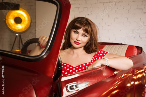 Beautiful sexy pin up girl sitting in the red car