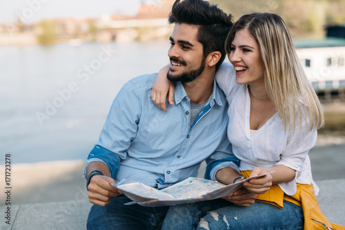 Happy tourist couple with map traveling outdoors