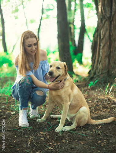 In autumn forest meadow preaty little girl lying on the grass with her golden retriever in the autumn forest. submissiveness photo