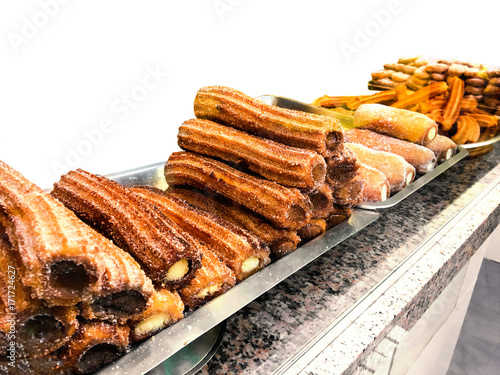 Churros on a market stall in a bakery shop. Sweet Famous Spanish dessert with chocolate sauce close up.