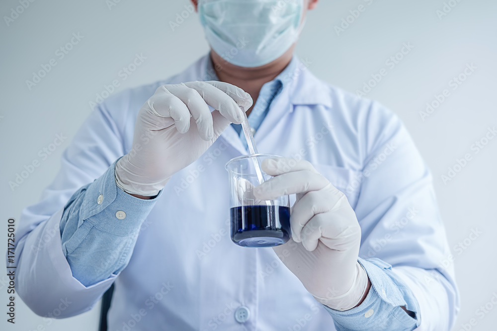 Medical or scientific researcher or man doctor looking at a test tube of clear solution in a laboratory Medical or scientific researcher or man doctor looking at a test tube of clear solution in a laboratory