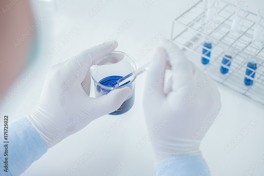 Fototapeta premium Medical or scientific researcher or man doctor looking at a test tube of clear solution in a laboratory