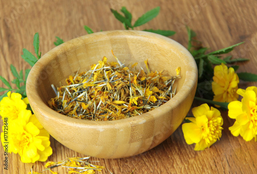 Calendula herb, yellow flower or herb dried in a wooden bowl for tea
