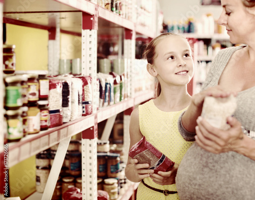 Woman with daughter are choosing fresh goods in food department
