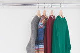 Warm woolen sweaters hanging on wooden hangers in the closet.