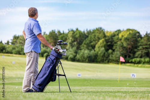 Senior man standing proudly on a golf club.