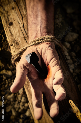 Close up of bloody hand nailed to cross