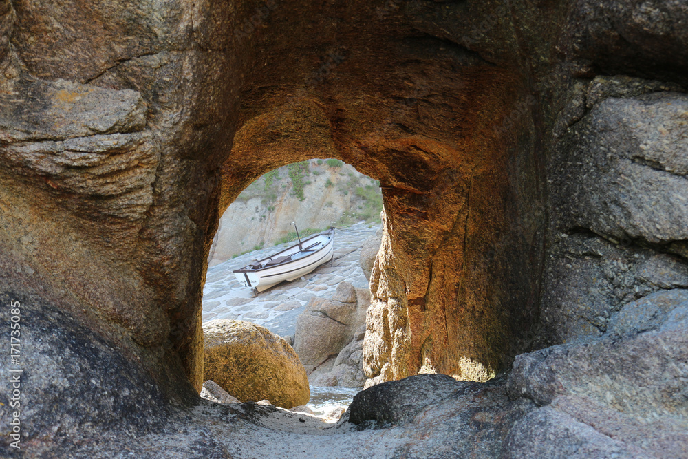 fishing boat on a launch slide, seen through a tunnel cut in rock, in Cornwall, UK, where fishing remains an important part of economy, but most of the catch is exported to France; July 2015