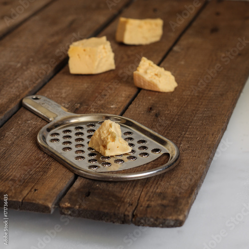 a piece of cheese and grater - on a wooden surface photo