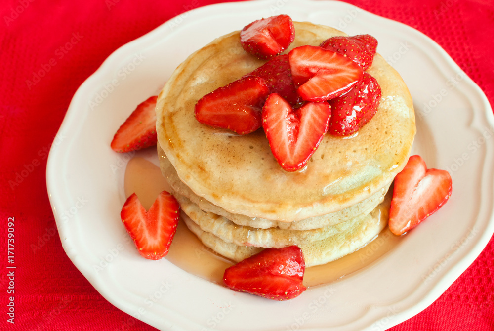 Pancakes with strawberries and syrup on red background. Selective focus.