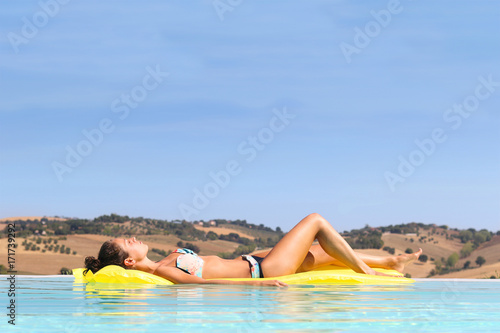 Young woman relaxing on air mattress in an infinity pool