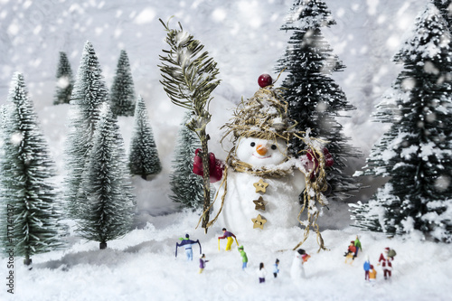 Snowman and miniature people in pine woods during winter © ArtBackground