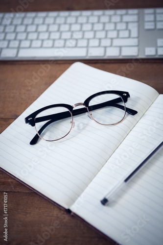 Close up of diary with pen and eyeglasses by keyboard
