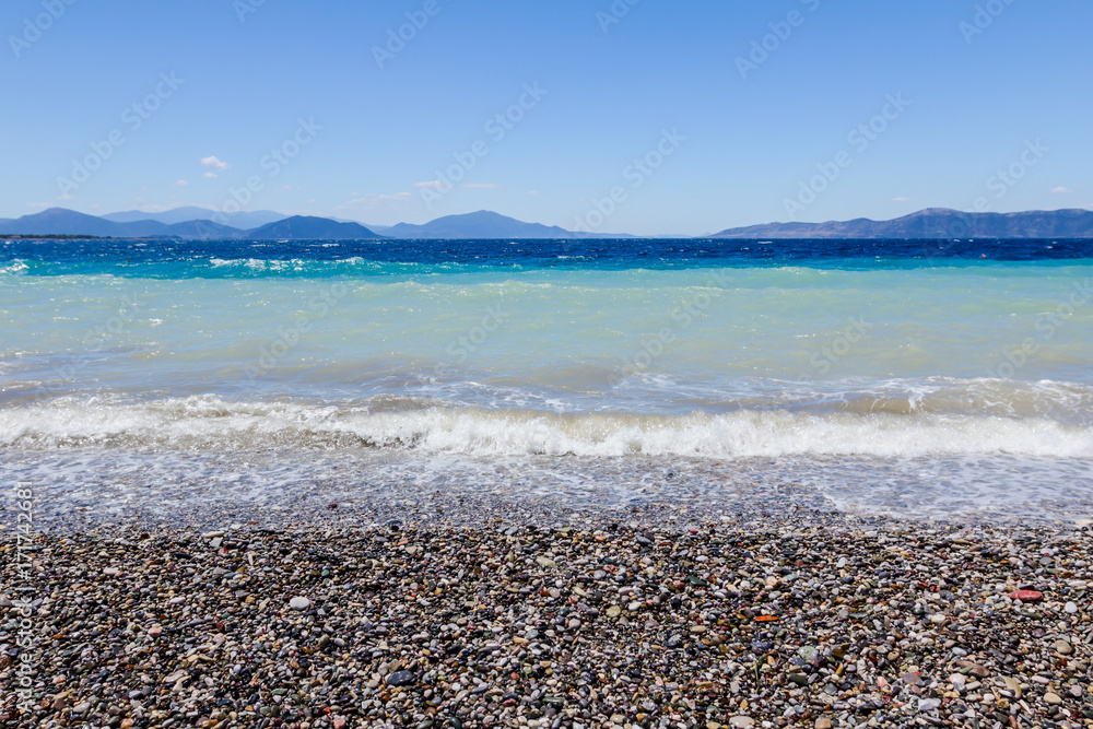 Sea is breaking foamy waves against pebbles on a beach, coast Sea is breaking foamy waves against pebbles on a beach, coast