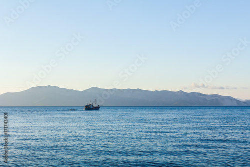 Fishing boat is crossing over calm sea