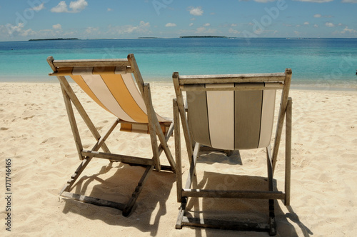 Two Beach chairs looking out to the beautiful blue Indian Ocean  sitting on golden soft sand in the Maldives