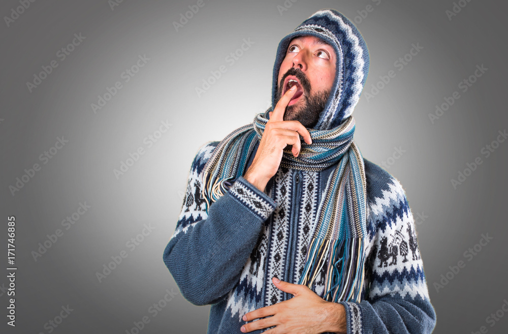 Man with winter clothes making surprise gesture on grey background Man with winter clothes making surprise gesture on grey background
