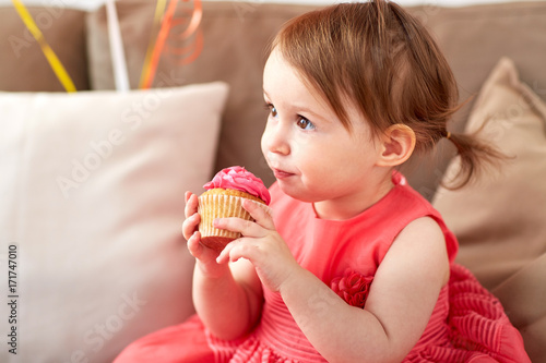 happy baby girl eating cupcake on birthday party