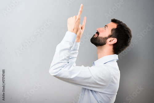 Handsome man with beard pointing up on textured background