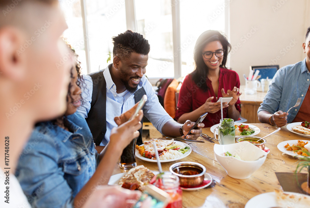 happy friends with smartphones at restaurant happy friends with smartphones at restaurant