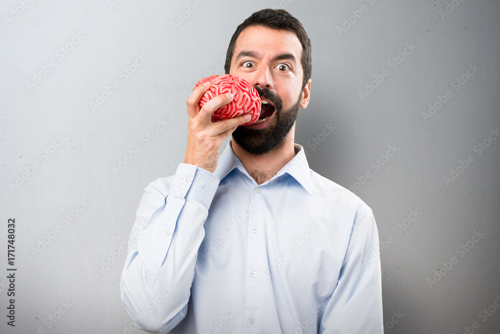 Handsome man with beard holding a brain on textured background Handsome man with beard holding a brain on textured background