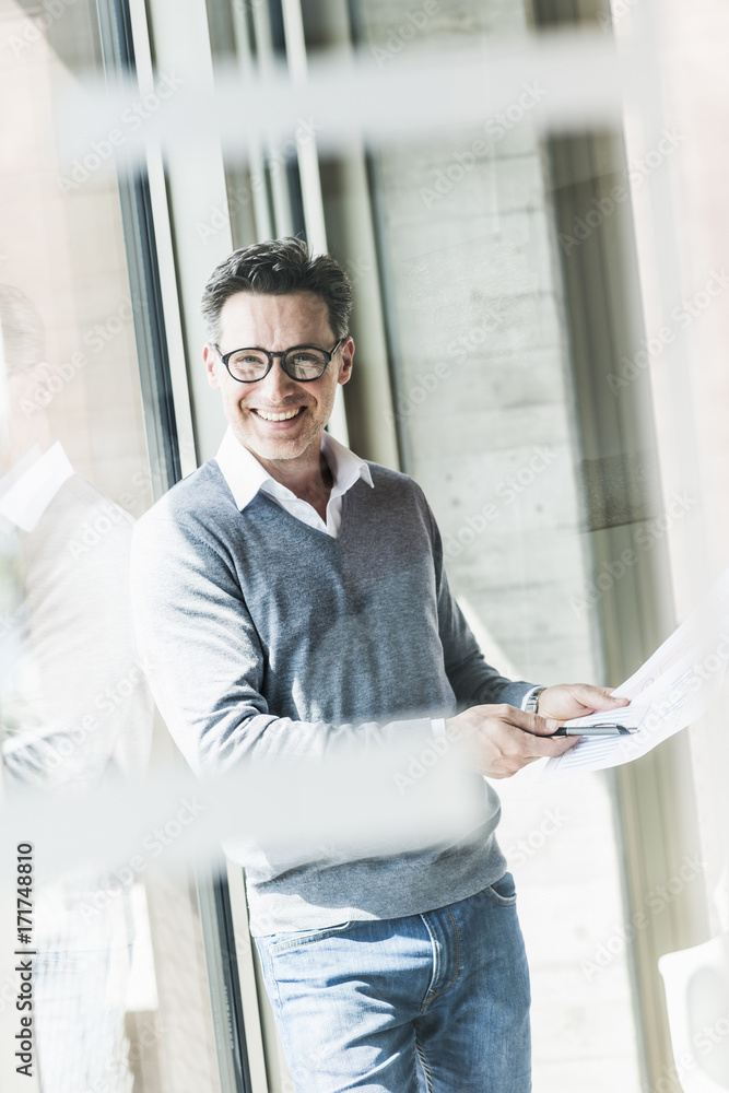 Portrait of smiling businessman with documents in an office Portrait of smiling businessman with documents in an office