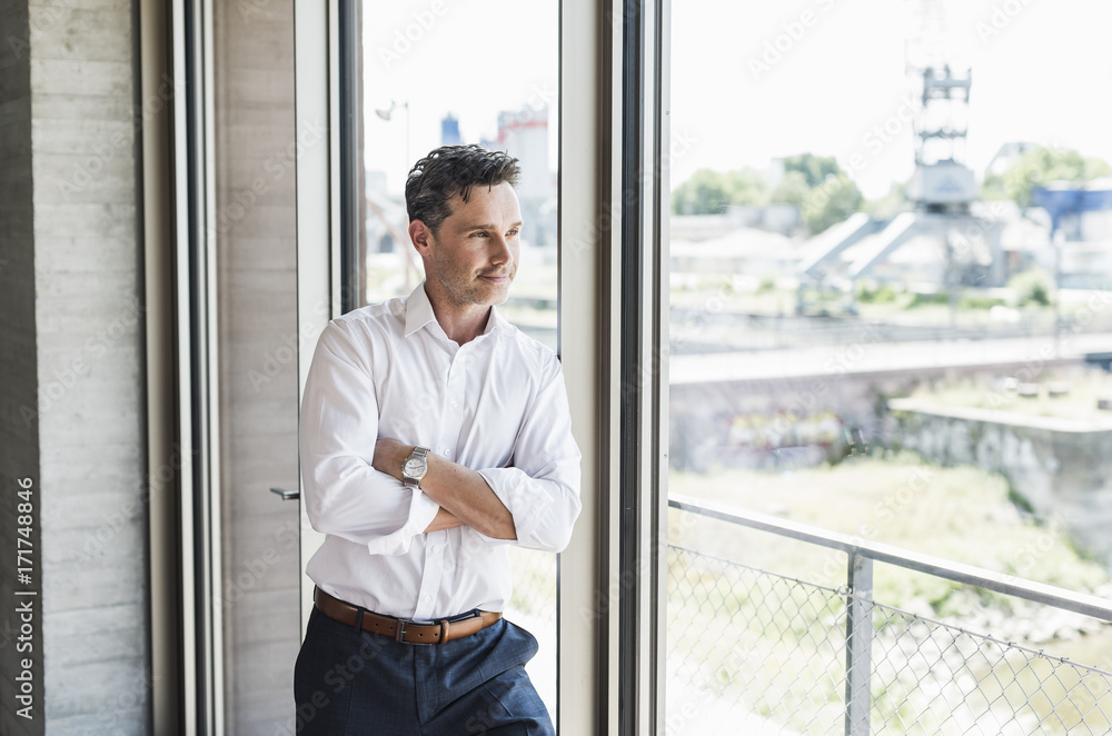 Portrait of confident businessman looking through window Portrait of confident businessman looking through window