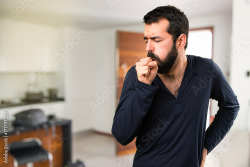 Handsome man with beard coughing a lot inside house photo