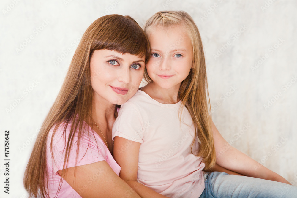 Portrait of beautiful mother and her daughter hugging, looking at camera. Happy family.. Portrait of beautiful mother and her daughter hugging, looking at camera. Happy family..