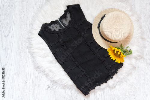 Black lace blouse. Hat and sunflower on white fur. Fashionable concept, top view photo