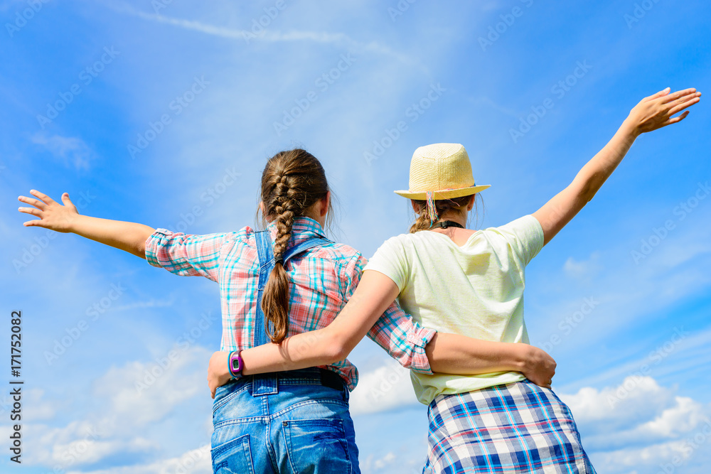 Happy friends with open arms under blue sky. Two girls having fun - relax outdoors. Friendship happiness summer holidays concept Happy friends with open arms under blue sky. Two girls having fun - relax outdoors. Friendship happiness summer holidays concept