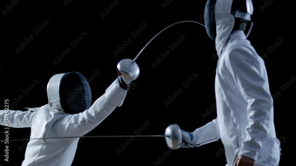 Two Professional Fencers Show Masterful Swordsmanship in their Foil Fight. They Attack, Defend, Leap and Thrust and Lunge. Shot Isolated on Black Background  and in Slow Motion. 