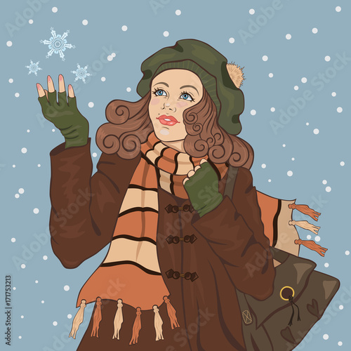 Young girl in a warm coat catches a snowflake.