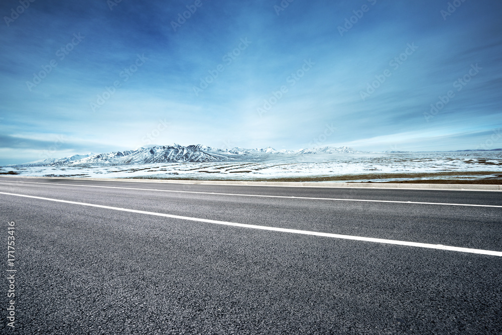 Fototapeta premium empty asphalt road with snow mountains in blue sky