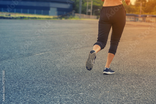 Sporty woman running on road at sunset. Fitness and workout wellness concept.