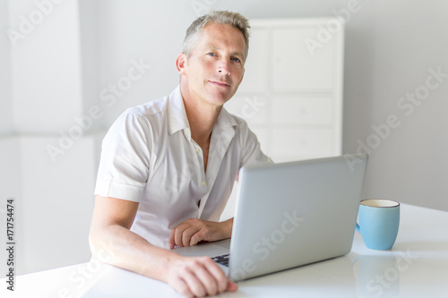 Mature Man Using Laptop On Desk At Home