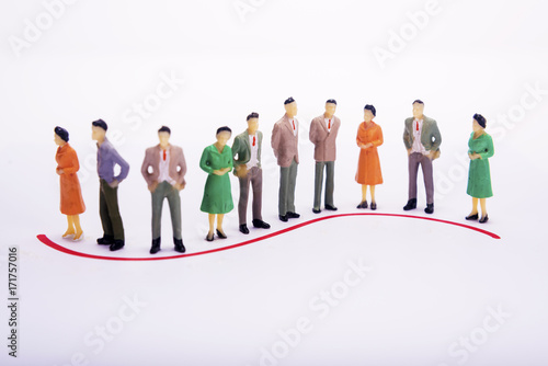 Group of miniature people over white background standing in line or circle.