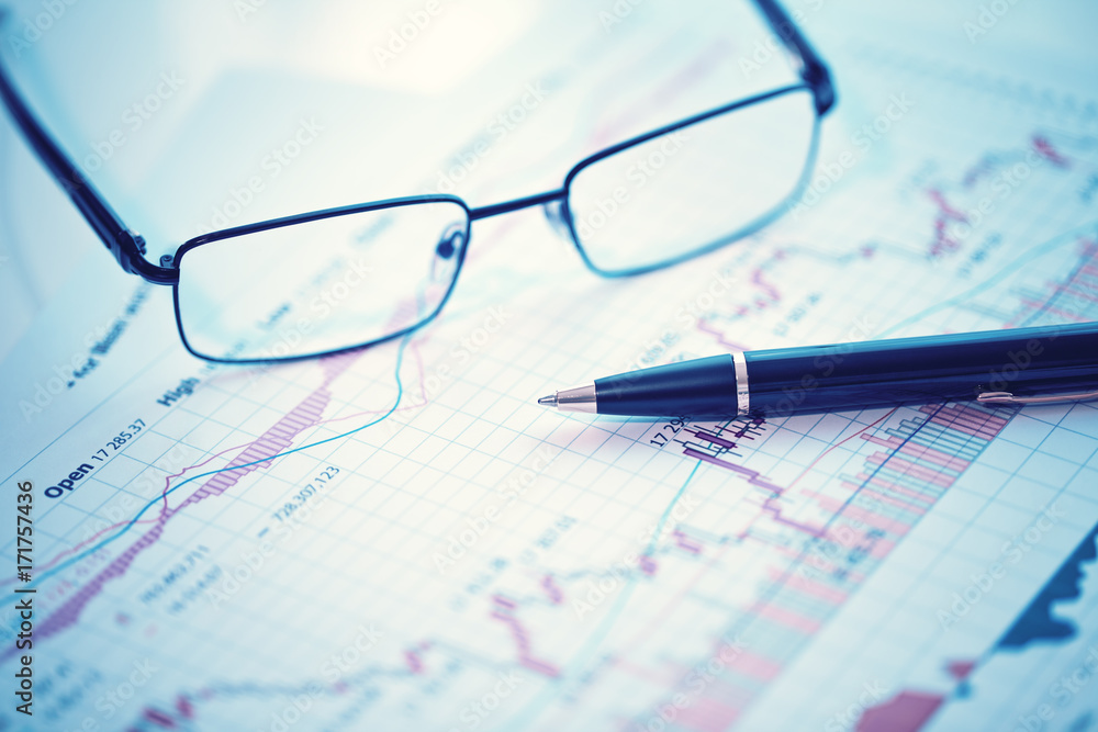 Pen and glasses on financial chart business concept analysis of sales plan business report business work station with paperwork Pen and glasses on financial chart business concept analysis of sales plan business report business work station with paperwork