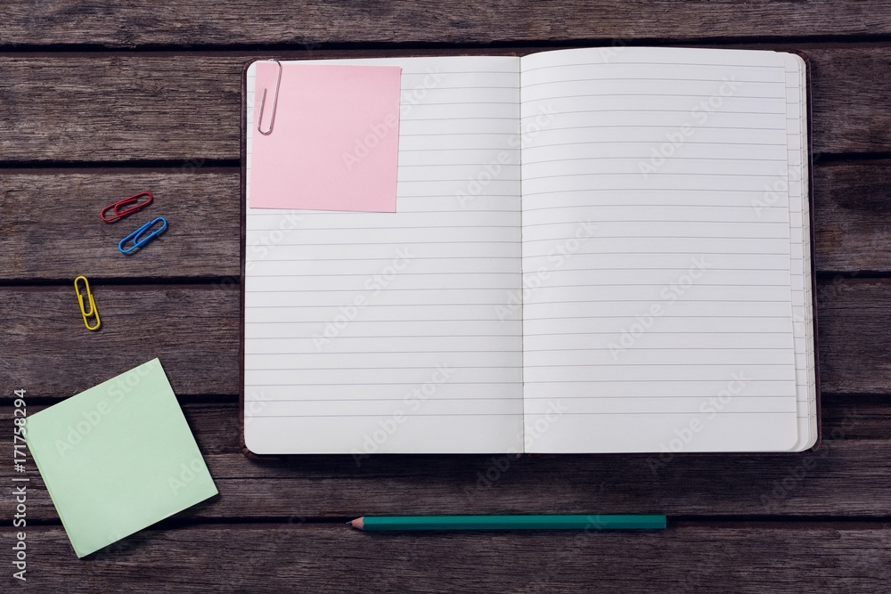 Diary, sticky notes, pencil and paper clip on wooden table Diary, sticky notes, pencil and paper clip on wooden table