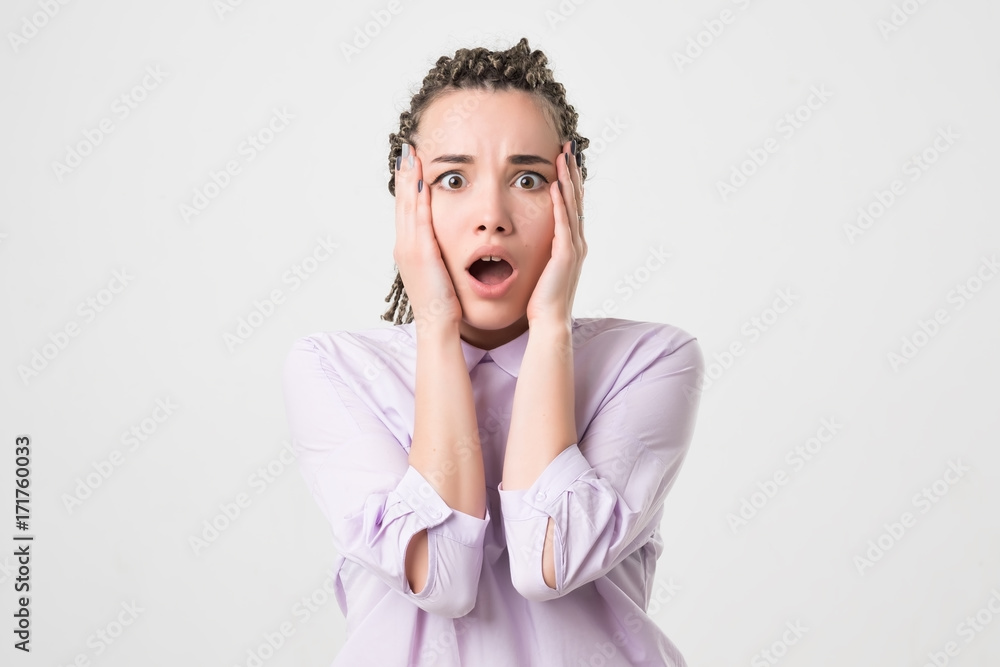young horrified woman closing her mouth with hands over white background young horrified woman closing her mouth with hands over white background