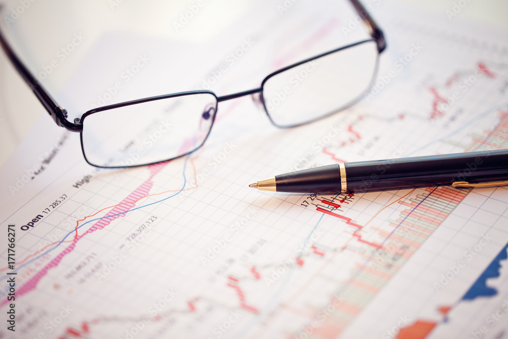 Pen and glasses on financial chart business concept analysis of sales plan business report business work station with paperwork Pen and glasses on financial chart business concept analysis of sales plan business report business work station with paperwork