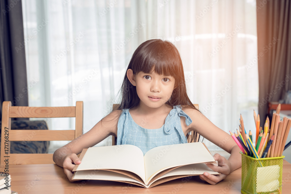 Child girl reading a book on the table in the house Child girl reading a book on the table in the house