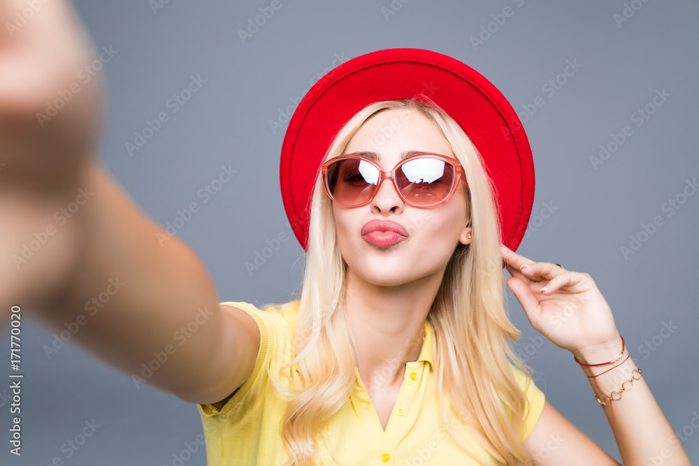 Young beautiful fashion woman take selfie from hands phone on gray background Young beautiful fashion woman take selfie from hands phone on gray background