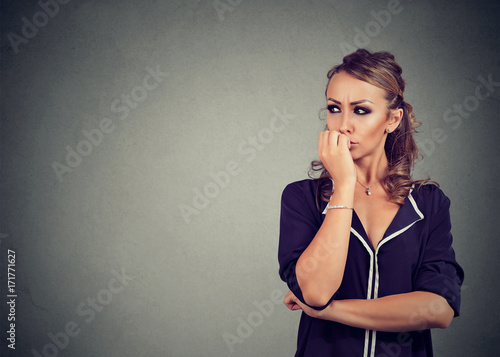 Preoccupied anxious woman biting her fingernails looking to the side