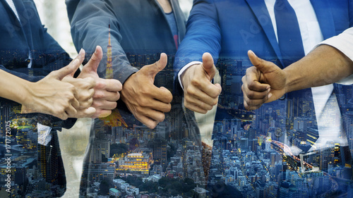 thump up hand from the group of business people with the overlay top view of nighttime modern city background.