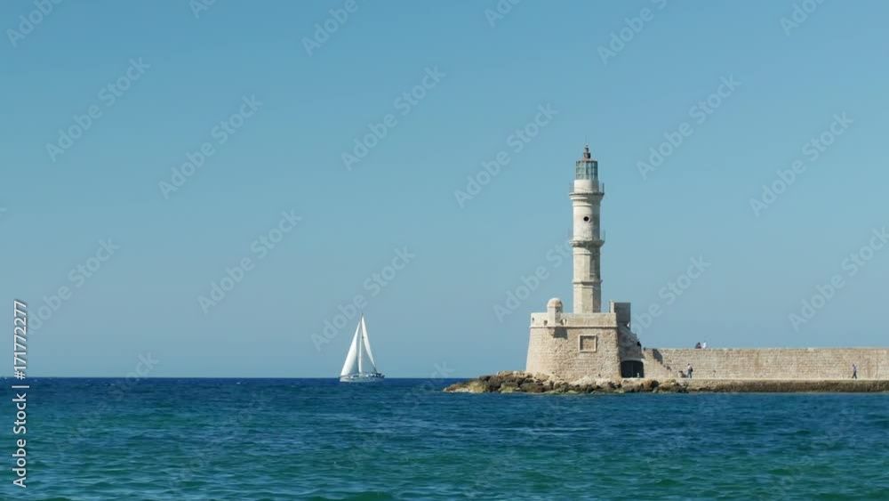 Sail boat passing by Chania's lighthouse. Panning shot. Sail boat passing by Chania's lighthouse. Panning shot.
