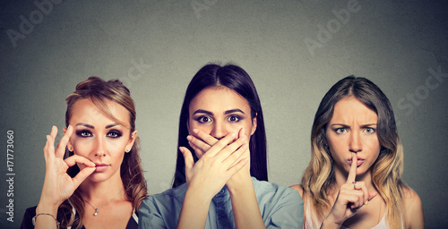 Keep a secret be quiet concept. Three secretive young women keeping mouth shut. photo