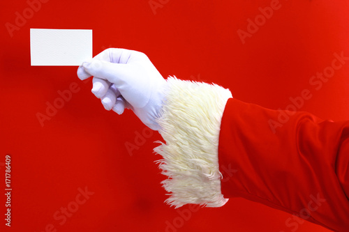 Santa Claus hand presenting your christmas text or product over red background with copy space