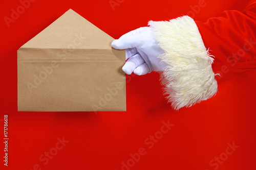 hand of Santa Claus with a letter on a red background
