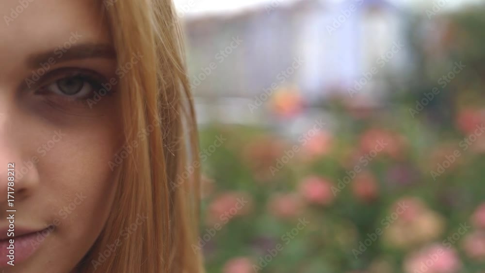 close-up portrait of a young blonde girl. female face on a background of roses in the garden. it's a nasty day 4k close-up portrait of a young blonde girl. female face on a background of roses in the garden. it's a nasty day 4k